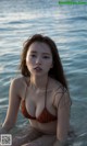 A woman in a brown bikini sitting in the water.