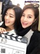 Two young women posing for a picture with a clapboard.