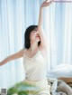 A woman sitting on a bed with her arms outstretched.