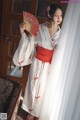 A woman in a white and red kimono holding a fan.