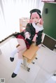 A woman in a school uniform sitting on a desk.