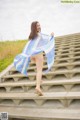 A woman in a blue and white striped shawl is walking up some steps.