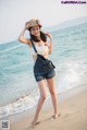 A woman standing on a beach next to the ocean.