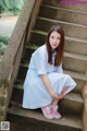 A woman in a blue and white striped dress sitting on some steps.